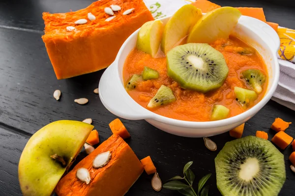 Purée de citrouille aux fruits sur fond de bois noir. Vue du dessus — Photo