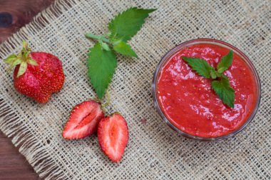 Çilek reçeli ile limon balm çuval bezi çerçevede bir ahşap bir masa üzerinde. Üstten Görünüm. Yakın çekim