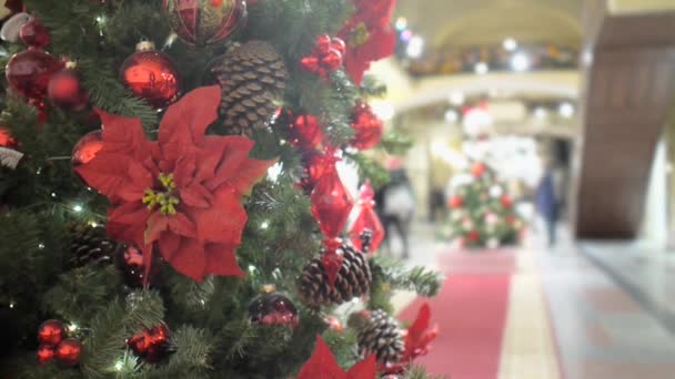 Kırmızı çiçek ve toplarla süslenmiş Noel ağacı GUM alışveriş merkezinin koridorunda duruyor. Ziyaretçiler bulanıklaşıyor — Stok video