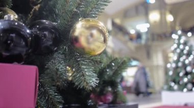 Altın ve siyah balonlarla süslenmiş bir Noel ağacı alışveriş merkezinin lobisinde duruyor.