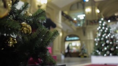 Altın ve siyah balonlarla süslenmiş bir Noel ağacı alışveriş merkezinin lobisinde duruyor.