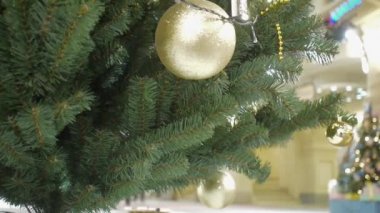 Altın toplarla süslenmiş bir Noel ağacı alışveriş merkezinin lobisinde duruyor.