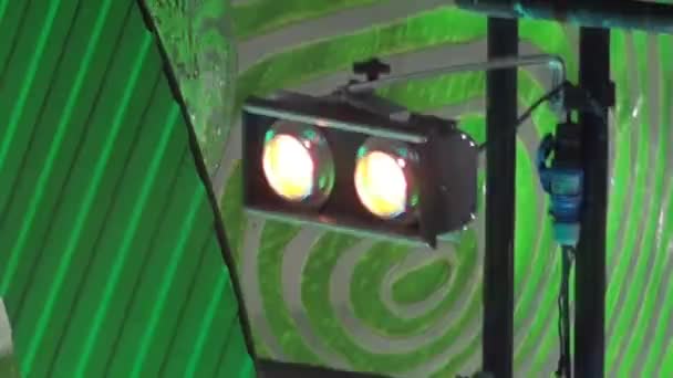 Duas luzes de palco estão piscando contra um fundo de palco verde em um loop — Vídeo de Stock
