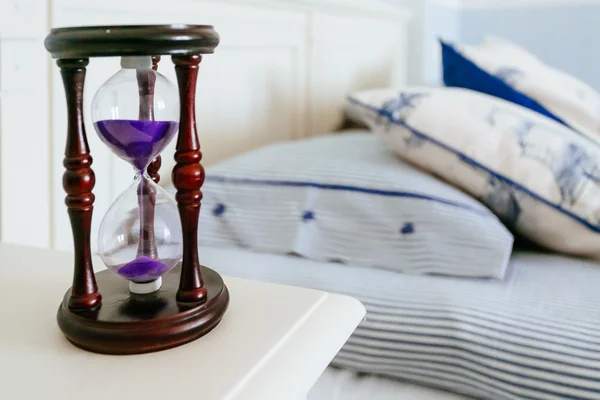 Sandglass op het nachtkastje in een slaapkamer — Stockfoto