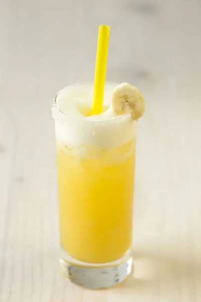 Жовтий лимонад з бананом в склянці на столі крупним планом — стокове фото