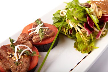 Dana madalyon domates ve beyaz bir plaka üzerinde ızgara patlıcan