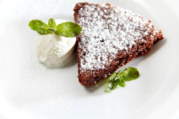Tort czekoladowy z lodami i cukier puder, szczegół na białym talerzu — Zdjęcie stockowe