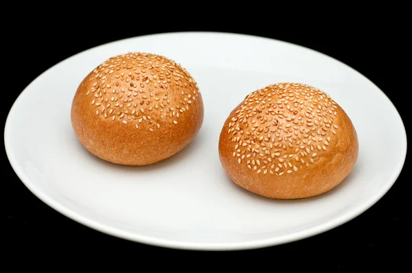 Dois pães de sanduíche com gergelim na placa branca — Fotografia de Stock