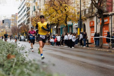 Alcoy, İspanya, 12-14-2025: Alcoy 'daki Camilo Sesto Caddesi' nden geçen yarım maraton koşucusu
