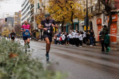 Alcoy, İspanya, 12-14-2025: Alcoy yarı maratonundaki cihaz ile performansı ölçen koşucu
