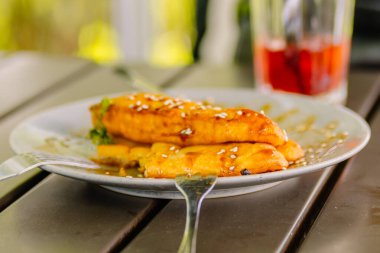 Tatlı karamelli kızarmış muz (Pisang Goreng) tatlı, üzeri parlak karamel sosuyla kaplı ve ahşap bir masada güzel servis edilir.