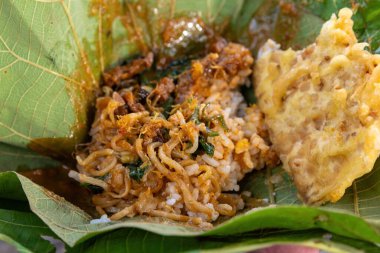 Nasi Pecel 'in yakın çekimi erişte ve meşe yaprağı tabağında kızarmış börek ile servis edilir. Geleneksel Endonezya sokak yemekleri yemeye hazır.