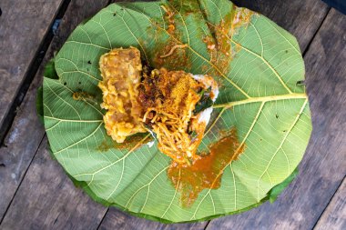 Nasi Pecel 'in yakın çekimi erişte ve meşe yaprağı tabağında kızarmış börek ile servis edilir. Geleneksel Endonezya sokak yemekleri yemeye hazır.