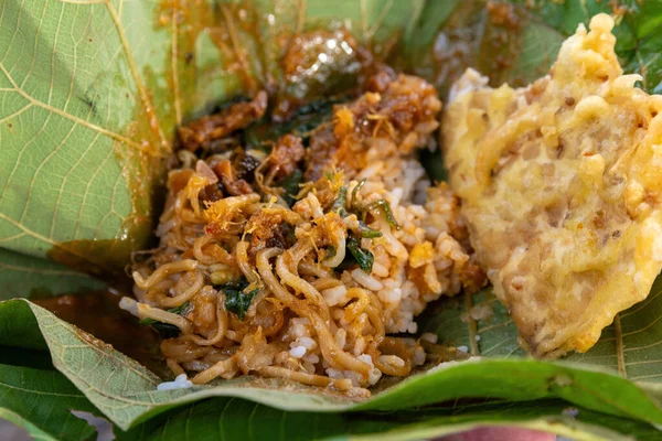 Nasi Pecel 'in yakın çekimi erişte ve meşe yaprağı tabağında kızarmış börek ile servis edilir. Geleneksel Endonezya sokak yemekleri yemeye hazır.