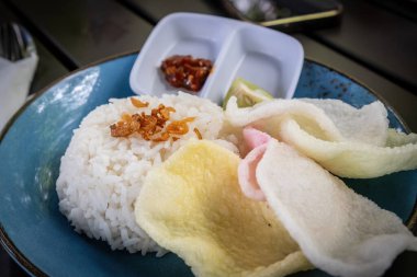 Üzerine kızarmış soğan, renkli kraker ve sambal soslu mis kokulu beyaz pirinç.