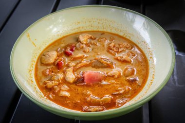 Kremalı, baharatlı portakallı körili, taze tavuk parçaları, mantarlar ve domatesler seramik kasede..