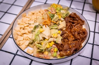 Sağlıklı ve canlı karışık sebzeler, lezzetli et dilimleri, edamame, mısır ve çıtır çıtır cipsler.