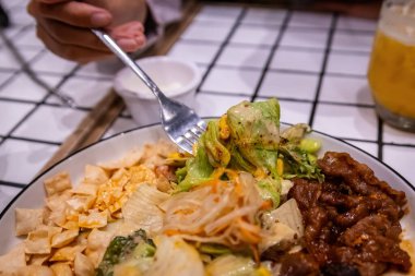 Sağlıklı bir füzyon yemeğinden taze salata ve mısırdan bir ısırık alan bir çatalın yakın çekimi.