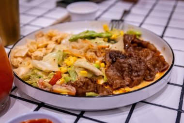 Sağlıklı ve canlı karışık sebzeler, lezzetli et dilimleri, edamame, mısır ve çıtır çıtır cipsler.