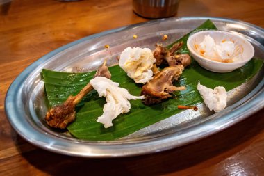 Endonezya yemeğinden sonra arta kalan tavuk kemikleri ve kullanılmış mendiller.