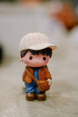 Sade bir arka planda şapka ve kahverengi ceket giyen sevimli minyatür bir erkek figürü.