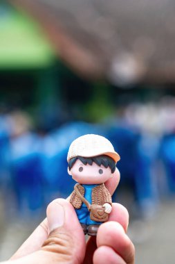 Kalabalık geçmişi bulanık, minyatür bir çocuğu kucaklayan bir elin yakın çekimi.