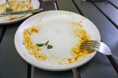 Bir kafede doyurucu bir yemek yedikten sonra arta kalan karamel soslu ve çatal bıçaklı beyaz tabak.