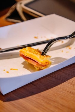 Jambon ve Peynirli Tost 'un Son Isırığı Bir Yemek Sonrası Beyaz Kağıt Tepsi Üzerinde Çatalla Tutuldu