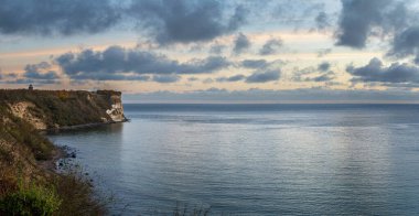 Almanya 'nın Rugen Adası' ndaki Cape Arkona 'da bulunan sarp beyaz tebeşir kayalıkları ve sonbahar bitkileri, arka plandaki ağaçların tepelerinde kısmen görülebilen bir sinyal kulesi (Peilturm) bulunuyor..
