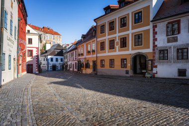 Cesky Krumlov, Czechia - November 23, 2025: Antique old town on River Vltava. Picturesque landscape with cosy colourful houses the river banks among green trees. Sunny  day blue sky clouds.