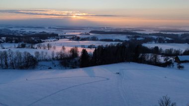 Gün batımında karlı kırsal manzaranın havadan görüntüsü.