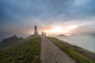 St. Primoz Kilisesi ve Felicijan, Jamnik, Slovenya manzaralı bir manzara. Jamnik Kilisesi, Kranj yakınlarındaki Kamnik-Savinja Alpleri 'nde 15. yüzyıldan kalma büyüleyici bir şapel. Sonbahar sisli sabah erkenden.