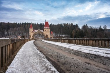 Neo-gotik kuleleri olan tarihi taş baraj Les Kralovstvi ve kışın kar manzaralı geçit.