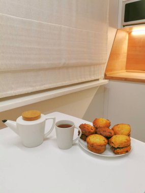 Beyaz çay fincanı ve çaydanlıkla güzel servis edilmiş ev yapımı kekler. Ev yapımı ve masa ayarlama kavramı