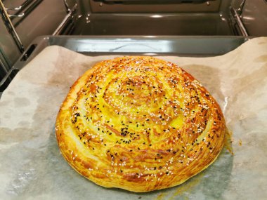 Üçüncü adım. Ispanaklı ve ricotta peynirli Burek. Peynirli yuvarlak turta, otlar, sarısı yağlı, susam tohumları serpiştirilmiş. Lezzetli Balkan turtası Borek. Vejetaryen yemekleri..