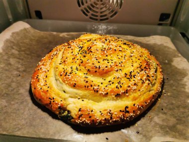 Üçüncü adım. Ispanaklı ve ricotta peynirli Burek. Peynirli yuvarlak turta, otlar, sarısı yağlı, susam tohumları serpiştirilmiş. Lezzetli Balkan turtası Borek. Vejetaryen yemekleri..
