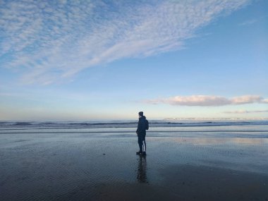 Fransa 'nın Deauville şehrinde Manş Denizi kıyısında deniz ve mavi gökyüzünün arka planına karşı bir gezgin. Fransa 'yı baştan başa dolaş.