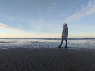 Fransa 'nın Deauville şehrinde Manş Denizi' nin deniz ve mavi gökyüzü kıyısında bir kız. Fransa 'yı dolaş. Kadın gezgin