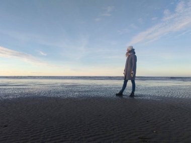 Fransa 'nın Deauville şehrinde Manş Denizi' nin deniz ve mavi gökyüzü kıyısında bir kız. Fransa 'yı dolaş. Kadın gezgin