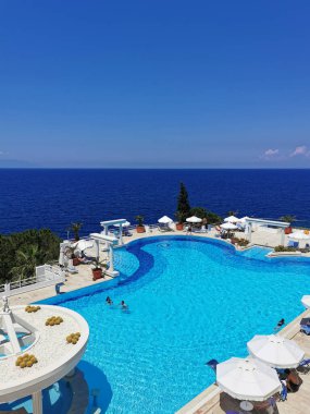 Mavi su ve deniz manzaralı lüks bir havuz. Türkiye 'nin Kusadasi beldesinde havuz kenarındaki güneş pansiyonları ve şemsiyeler