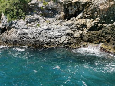 Türkiye 'nin Kusadasi kentinde gök mavisi deniz dalgaları kayalara çarptı