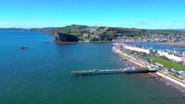 Teignmouth, Güney Devon, İngiltere: İHA arka planda Teign Nehri 'ni gösteren Grand Pier etrafında döner. Teignmouth, Birleşik Krallık 'ta popüler bir tatil beldesidir.).