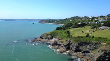 Torbay, Devon, İngiltere: İHA Thatcher Point 'ten Meadfoot sahiline doğru uçuyor ve uçurumlara bakan mülkleri gösteriyor. Torbay İngiltere 'de popüler bir tatil ve emeklilik alanıdır (1. klip 2).).