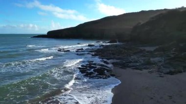 Man Sands, Güney Devon, İngiltere: DRONE VİEWS: İnsansız hava aracı bir uçurumdan düşmeden önce Man Sands plajı, dalgalar ve ön kıyı kayaları üzerinde alçaktan uçar. Plaj Brixham 'ın hemen güneyinde yer almaktadır ve köpek gezdiricileri, kanocular ve rüzgar sörfçüleri arasında popülerdir..