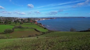 Holcombe, Güney Devon, İngiltere: DRONE VİEWS: İHA bir tepenin üzerinden kıyı şeridine doğru uçuyor ve orta alandaki Dawlish kasabasını gösteriyor. Dawlish, siyah kuğu nüfusuyla ünlü bir İngiltere turizm şehridir (Clip 1 / 2).).
