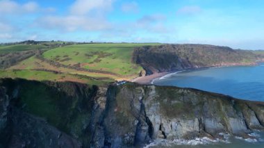 Man Sands, Güney Devon, İngiltere: DRONE VİEWS: İHA göl ve sahili ortaya çıkarmak için bir uçurumun üzerinden uçar. Man Sands, Brixham 'ın güneyindeki Güney Devon sahilinde yer almaktadır. Kumsalın arkasındaki göl kuşlar ve çim yılanları için bir sığınaktır..