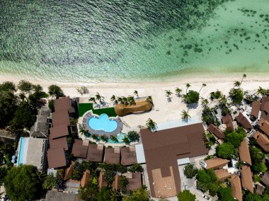 Havuzu, palmiyeleri ve güneşli bir gökyüzünün altında turkuaz plajı olan bir tatil köyünün insansız hava aracı görüntüsü. Rin Nai Sahili. Ko Pha Ngan, Tayland.