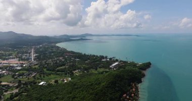 Yeşillik bitki örtüsü ve küçük binalarla çevrili deniz ve deniz manzarası. Maenam, Ko Samui, Tayland.