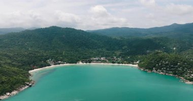 Turkuaz suları ve yemyeşil tepeler ve tropikal ormanlarla çevrili bir kıyı şeridi olan geniş bir koy. Tanga Nai Pan Yai Sahili. Ko Pha Ngan, Tayland.