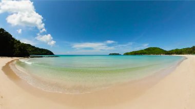 Şeffaf su ve dalgalar kumlu plaja çarpıyor. Mavi gökyüzü ve bulutlar. Diapela Sahili. El Nido. Palawan 'da. Filipinler.